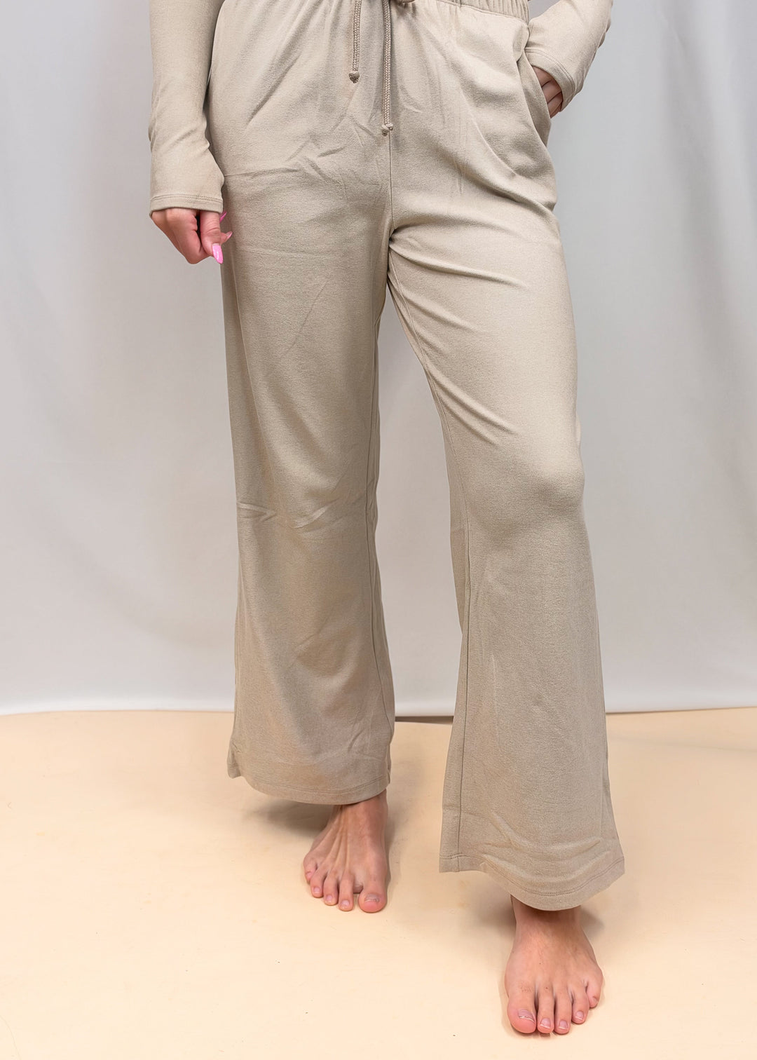 Woman shown from waist down wearing matching taupe set on plain background