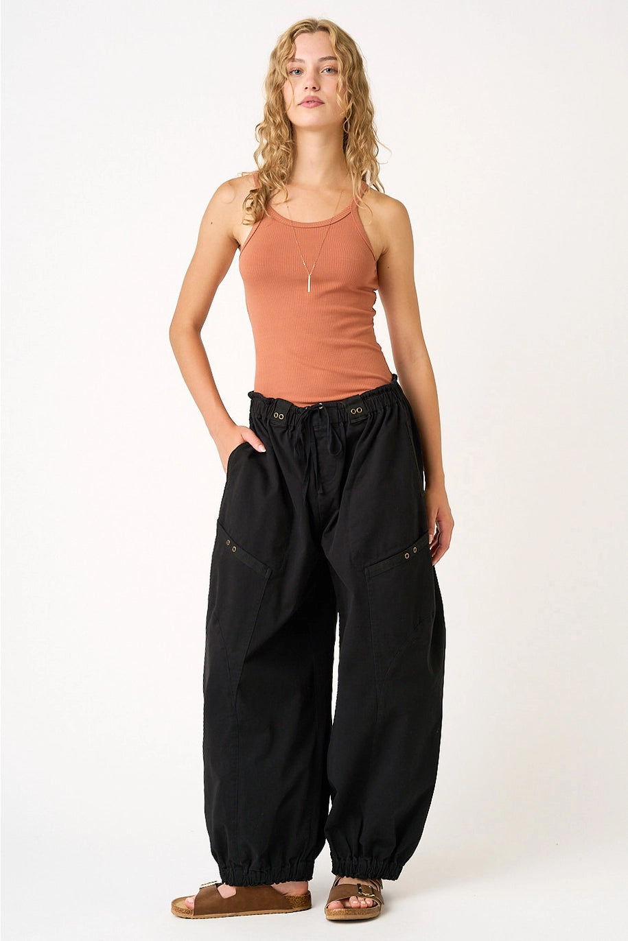 woman wearing black pants and orange tank on plain background