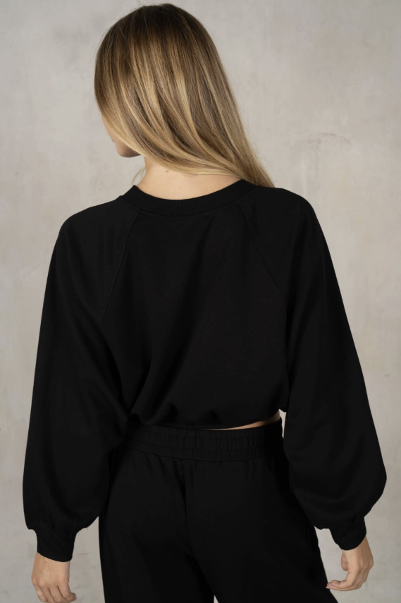 Person wearing a black oversized sweatshirt against a neutral background