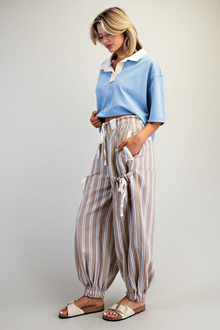 Woman wearing a light blue shirt and striped pants against a plain background