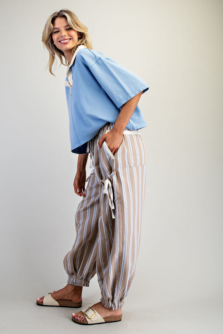 Woman wearing a blue top and striped pants on a plain background