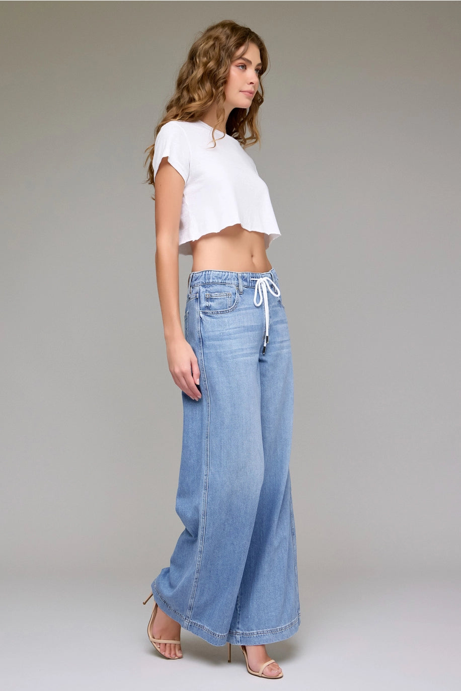 Woman wearing a white top and blue jeans on a plain background