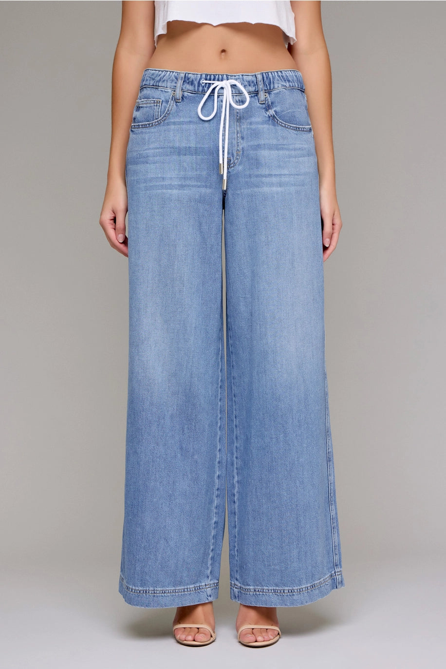 Wide-leg denim pants with a drawstring waist on a plain background