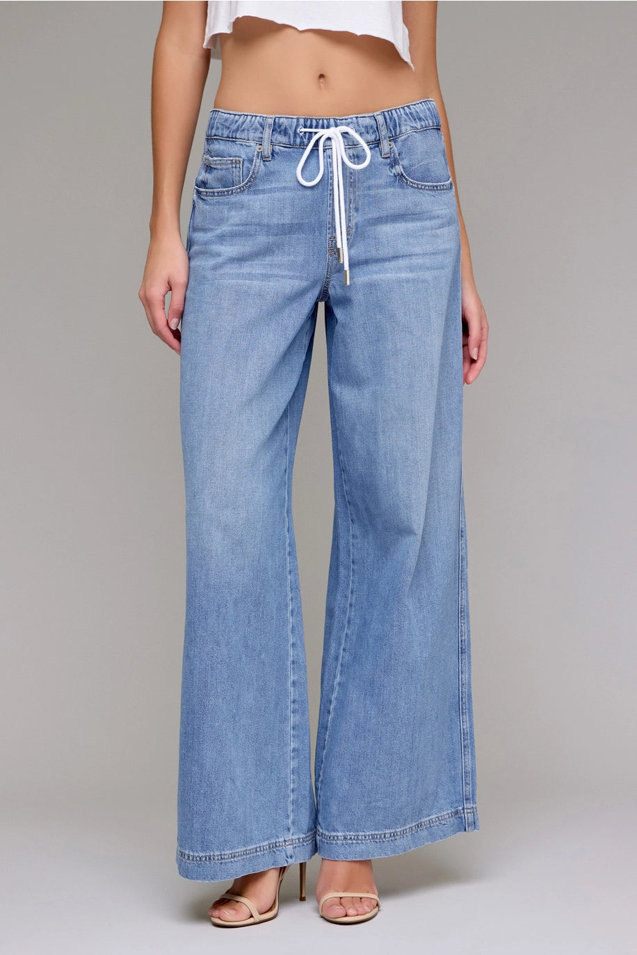 Light blue denim pants with a drawstring waist on a gray background