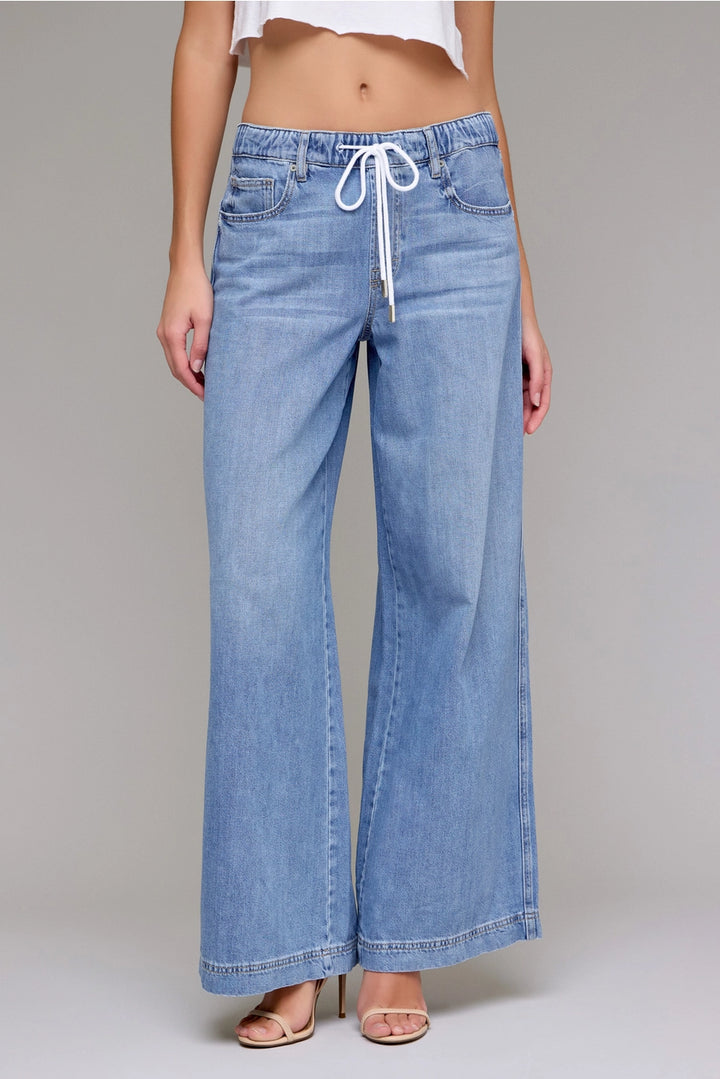Light blue denim pants with a drawstring waist on a gray background