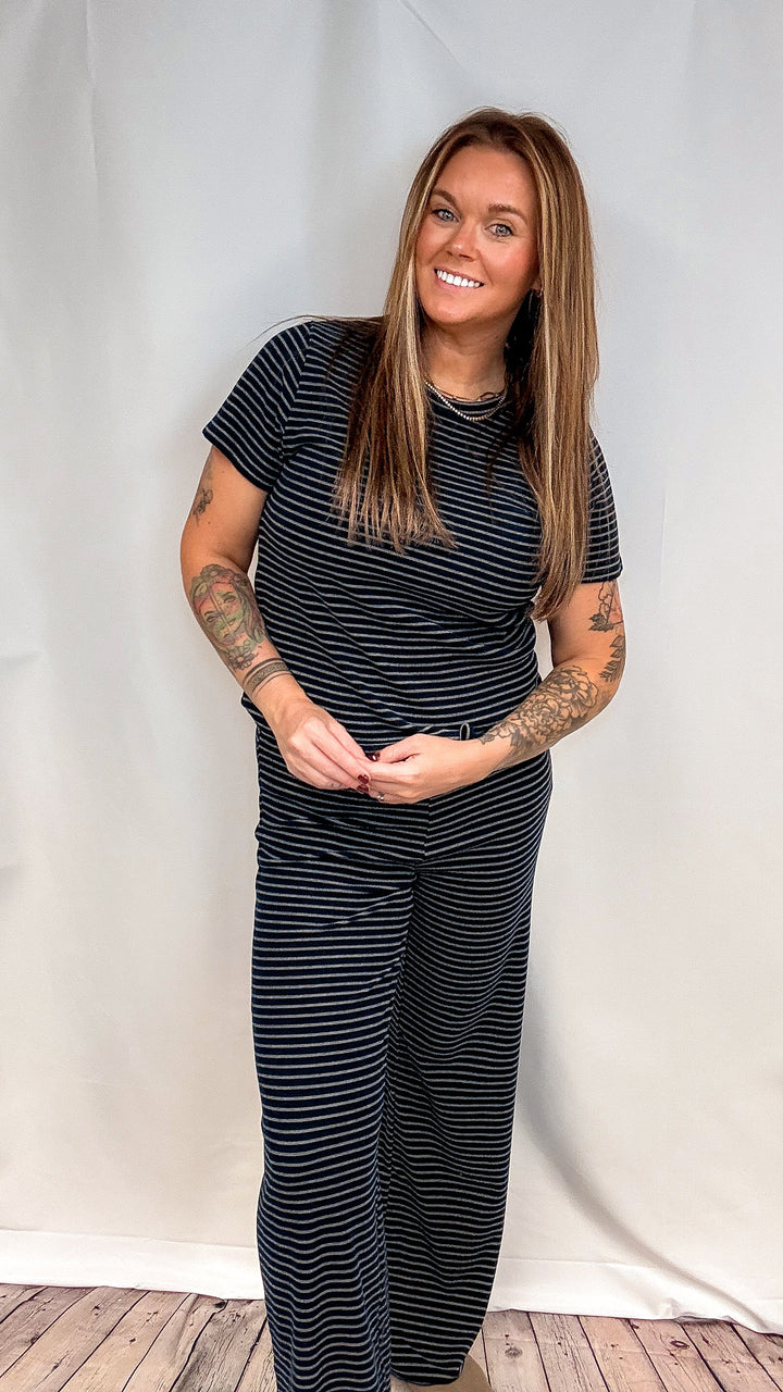 Woman wearing matching navy stripe set on plain background