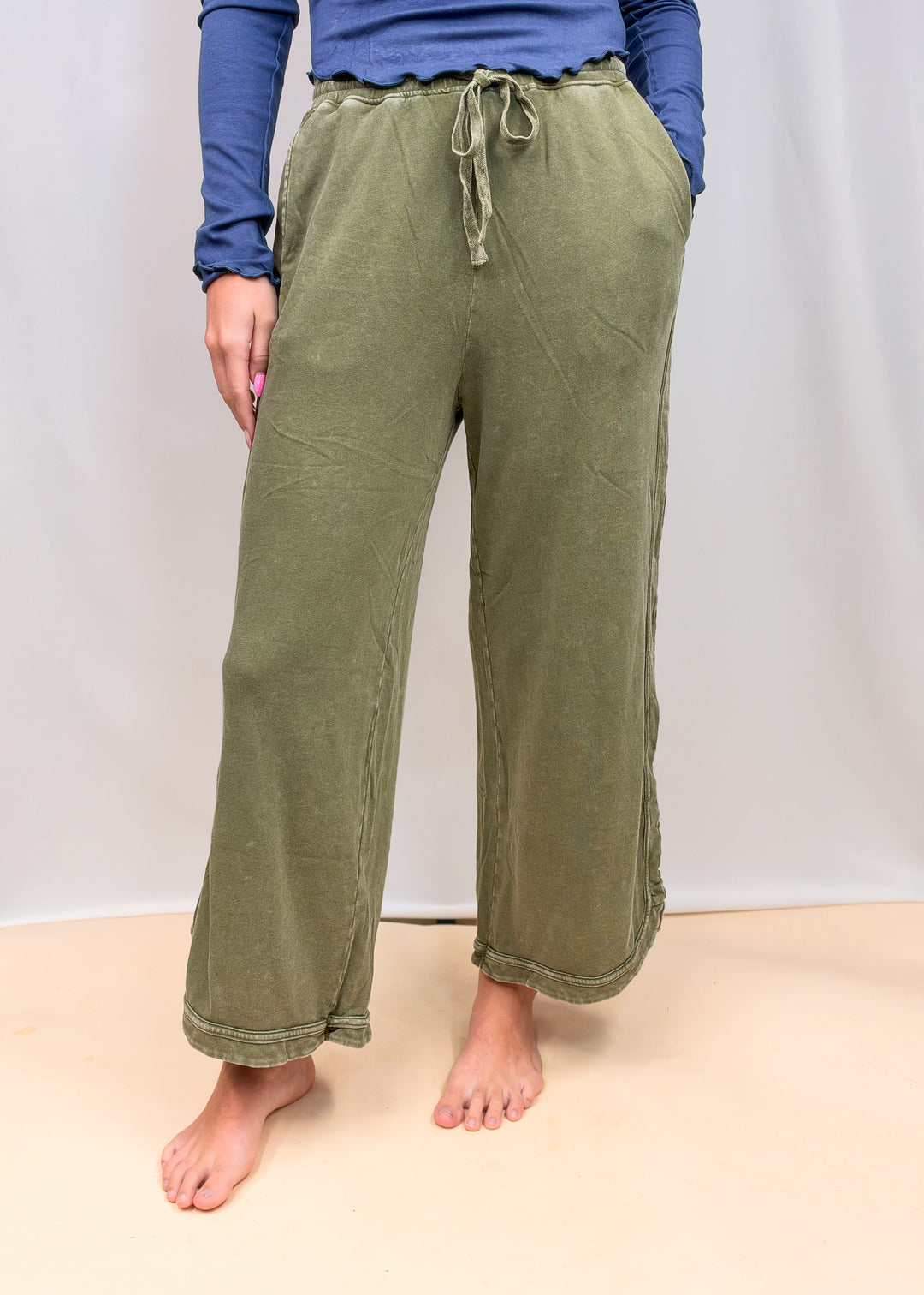 Woman wearing green sweatpants on plain background