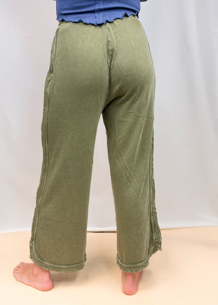 Woman shown from back wearing green sweatpants on plain background