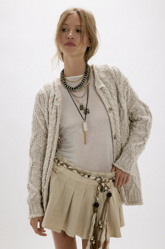 Woman wearing beige cardigan with white tee and skirt on white background
