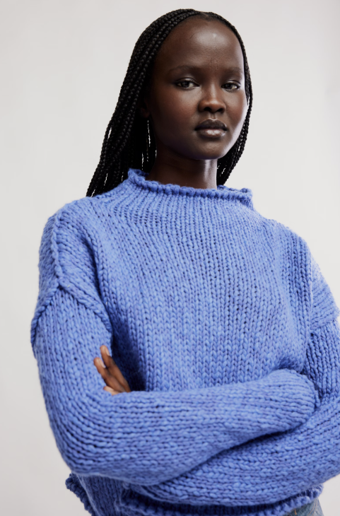 Woman wearing a blue knitted sweater against a plain background