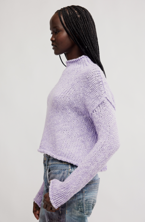 Woman wearing a light purple sweater and jeans on a white background