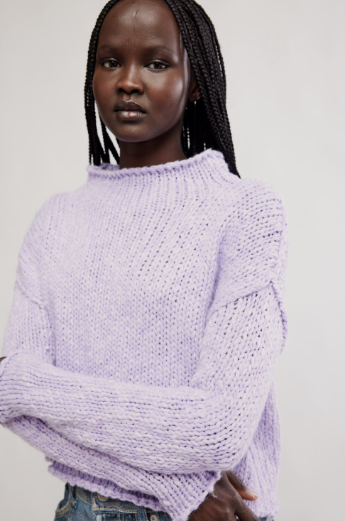 Woman wearing a light purple sweater against a plain background