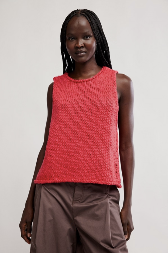 Woman wearing red tank and brown pants on white background