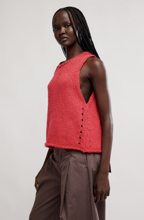 Woman wearing a red sleeveless top with a plain background