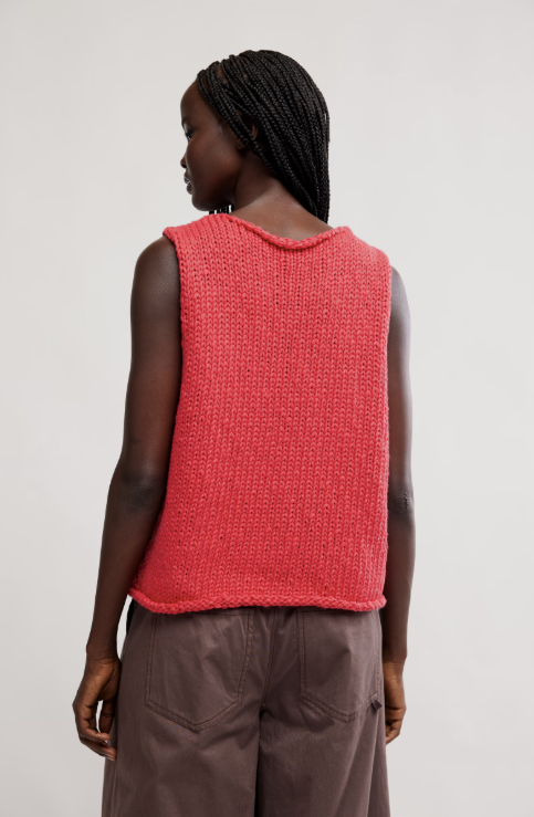 Person wearing a red knitted vest against a plain background