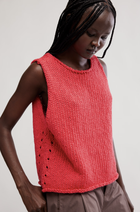 Person wearing a red knitted tank top against a plain background