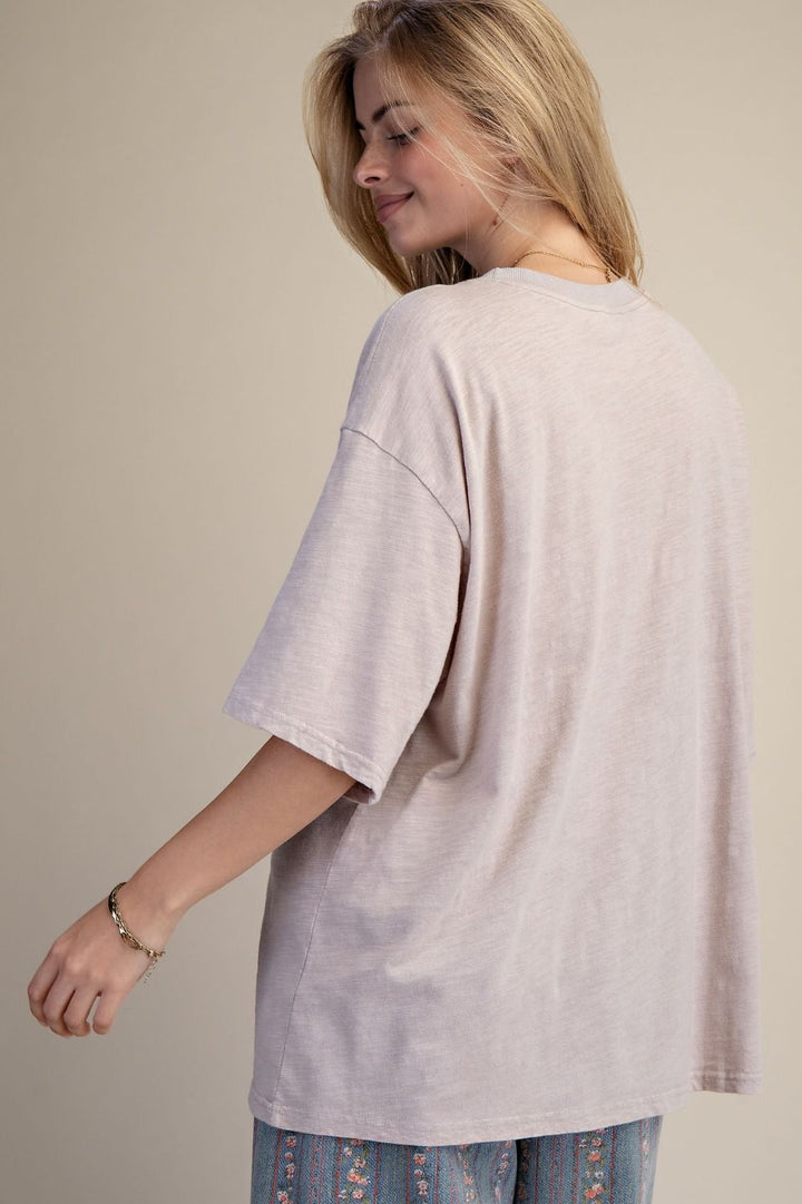 Woman wearing a light gray oversized shirt against a plain background