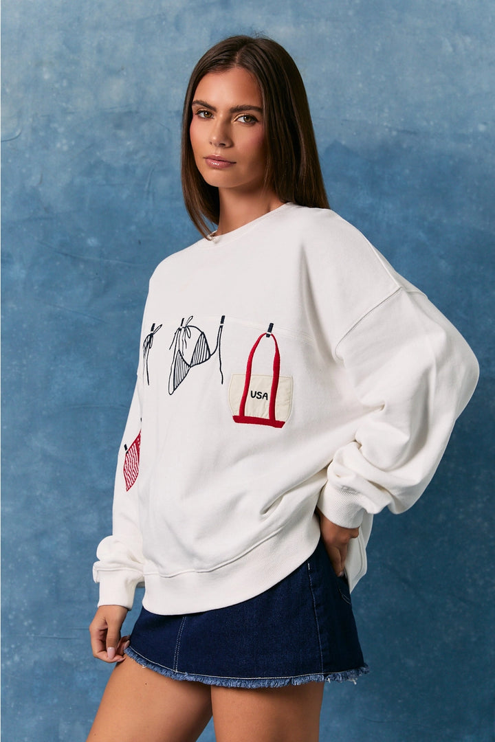 Woman wearing white sweatshirt with bathing suit graphics on plain background