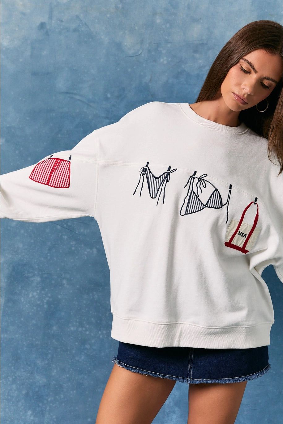 Woman wearing white sweatshirt with bathing suit graphics on plain background