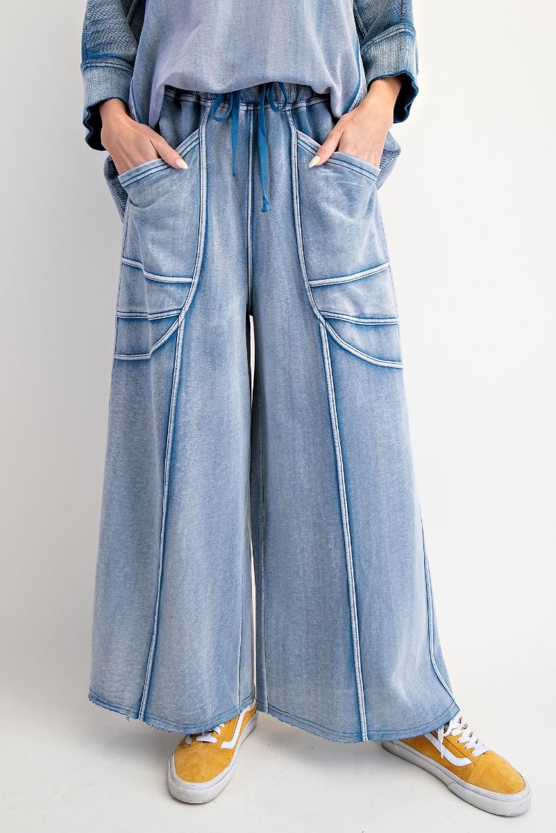 Person wearing light blue denim wide-leg pants with a plain background