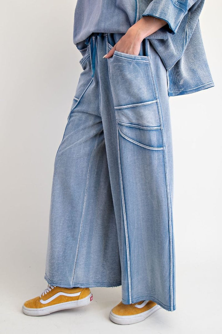 Person wearing a denim outfit with wide-leg pants and yellow sneakers on a white background