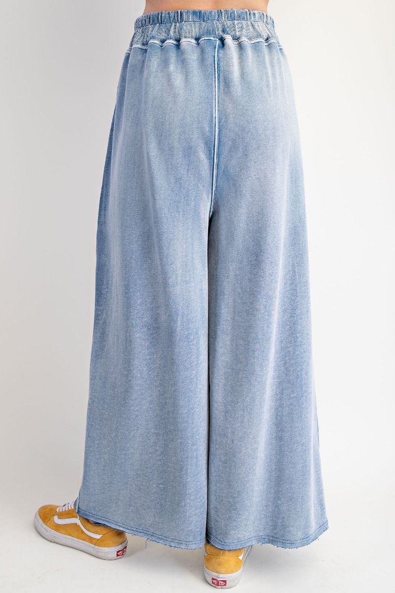 Light blue wide-leg jeans worn with yellow sneakers on a light gray background