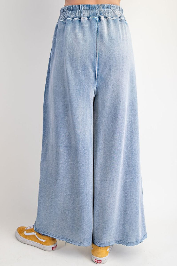 Light blue wide-leg jeans worn with yellow sneakers on a light gray background