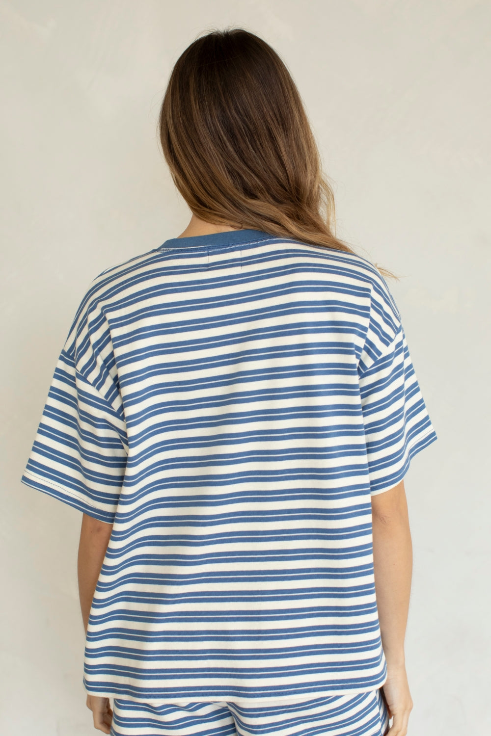 Back of woman wearing blue and white stripe set on plain background