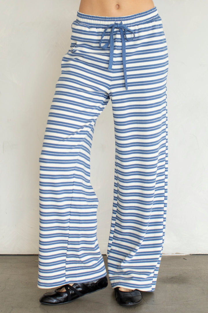 Woman wearing blue and white stripe pants on plain background