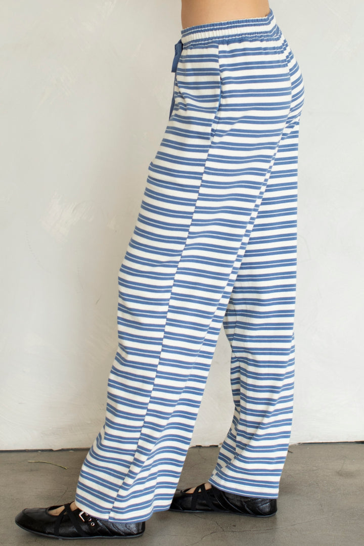 Woman wearing blue and white stripe pants on plain background