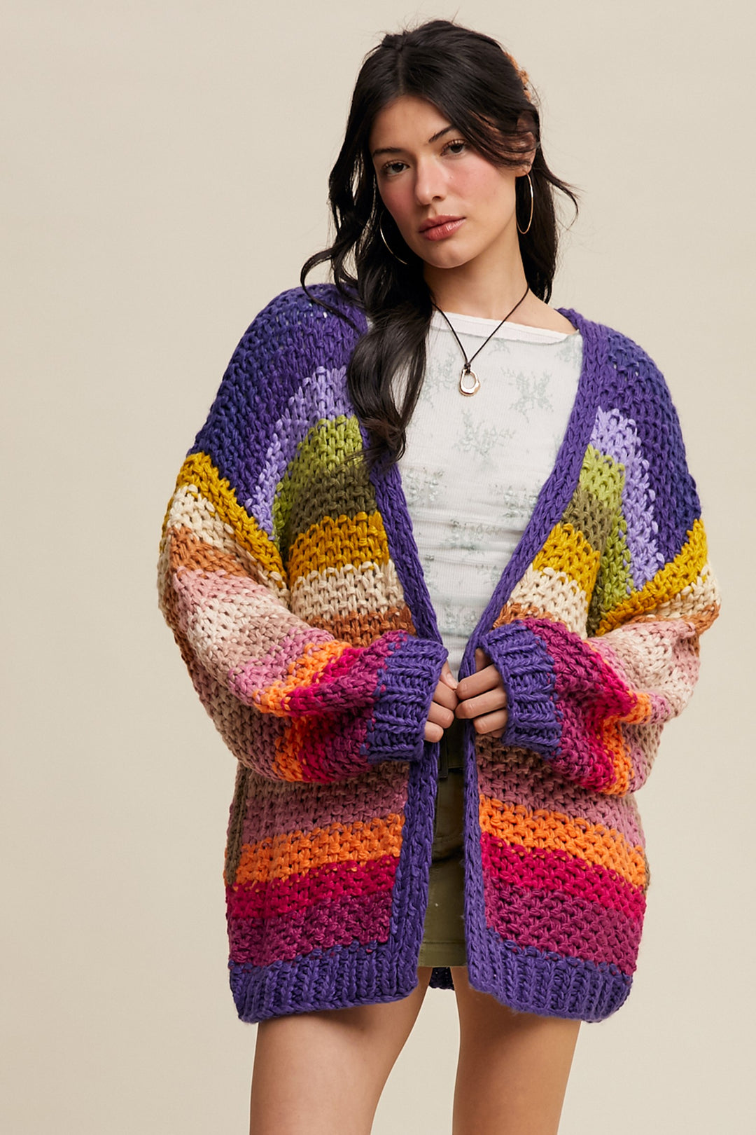 Woman wearing a colorful striped cardigan against a beige background