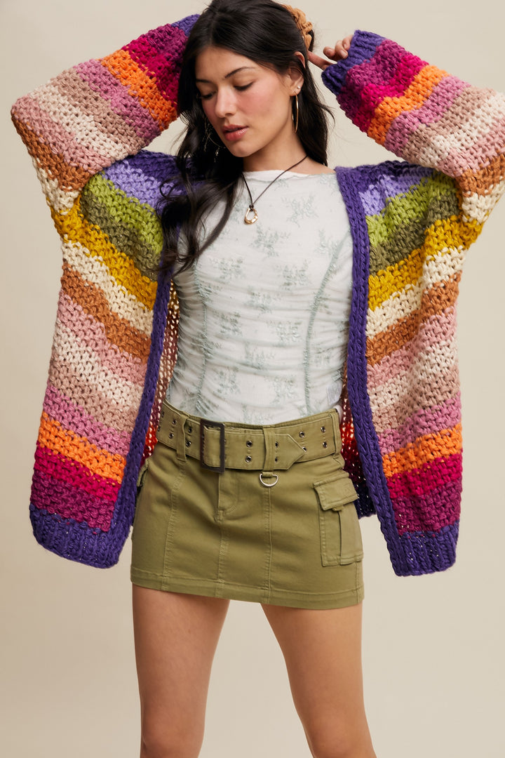 Woman wearing a colorful striped cardigan with a neutral background