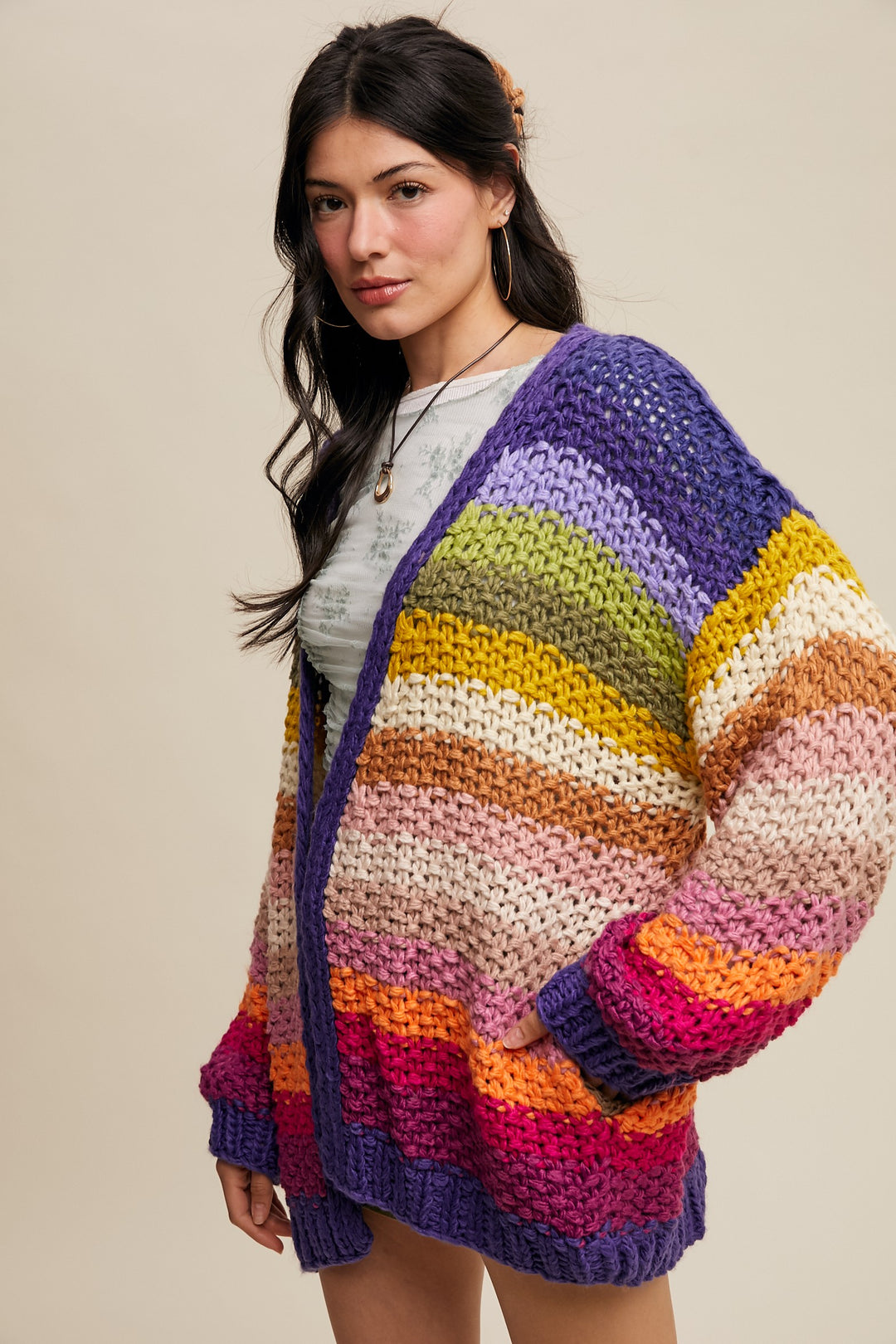 Woman wearing a colorful striped sweater against a beige background