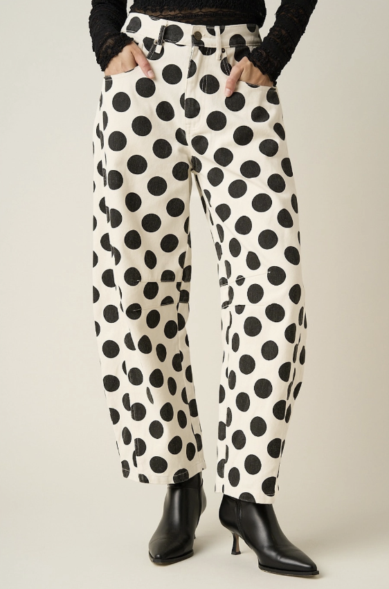 Woman wearing black and white polka dot pants on plain background