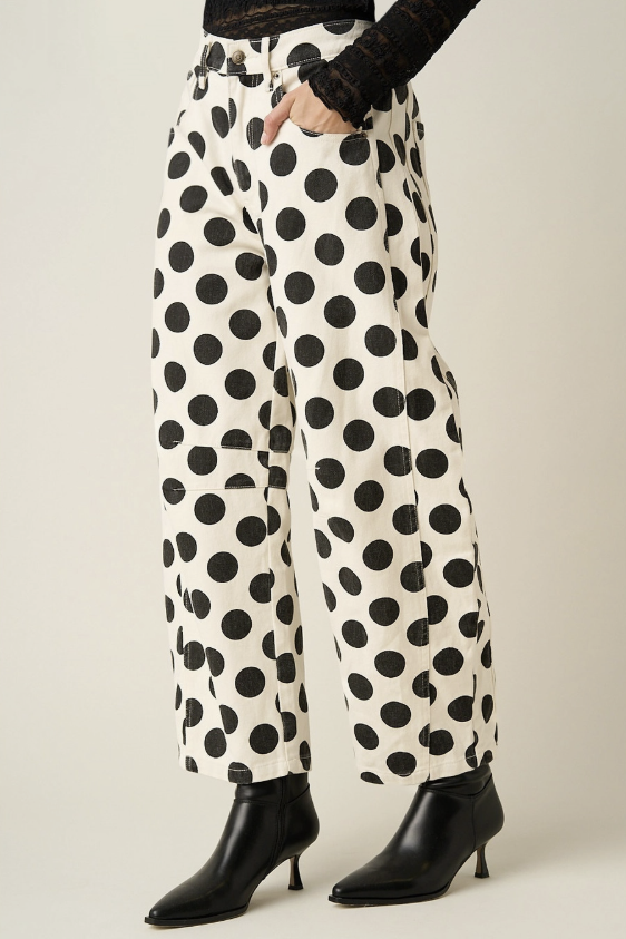 Woman wearing black and white polka dot pants on plain background