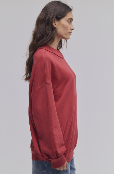 Woman wearing red mock neck sweatshirt and blue jeans on white background