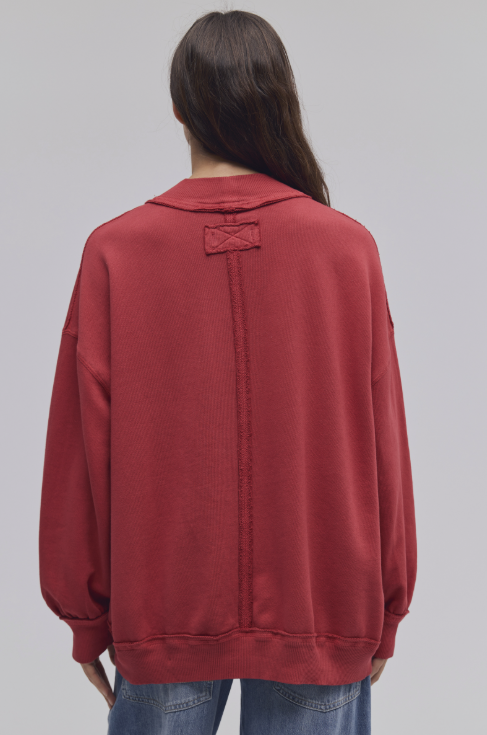 Woman shown from back wearing red sweatshirt and blue jeans on white background