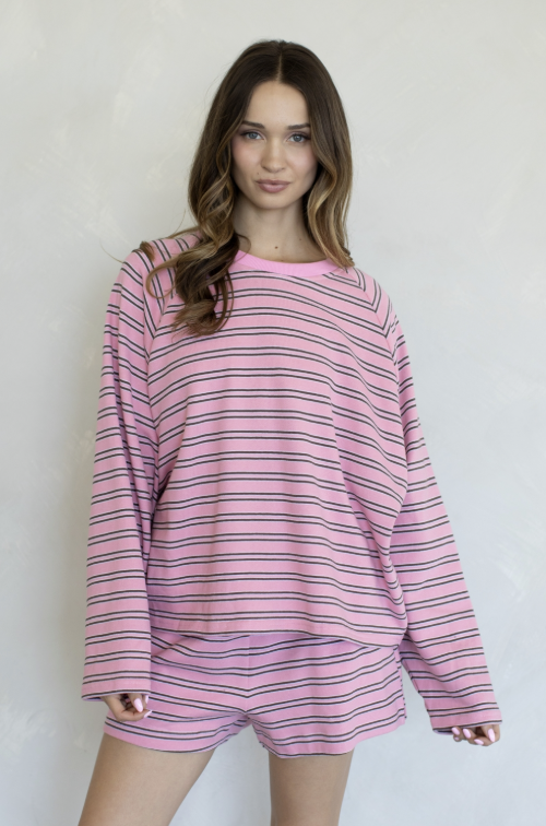 Woman wearing matching pink and brown stripe set on plain background