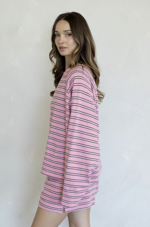 Woman wearing matching pink and brown stripe set on plain background