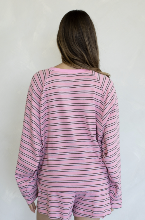 Woman shown from behind wearing matching pink and brown stripe set on plain background