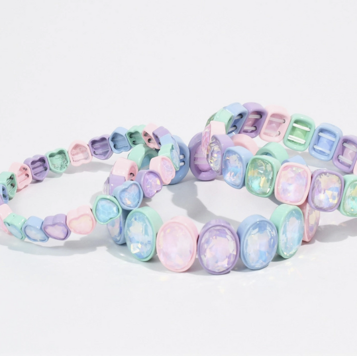 A set of pastel stretch bracelets with colorful, rounded, faceted beads in shades of pink, purple, blue, and mint green, arranged on a clean white background.