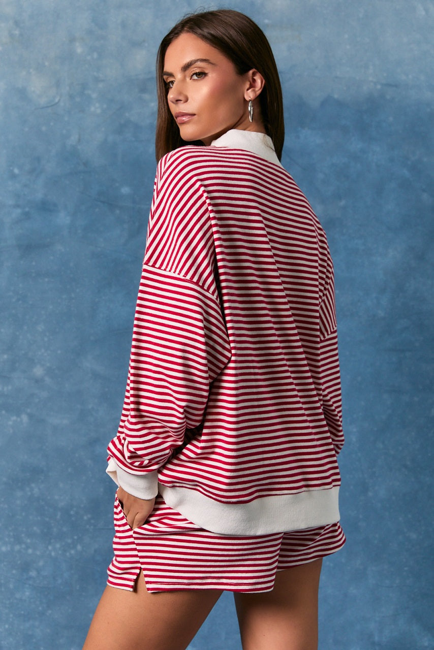Back of woman wearing matching red and white stripe top and shorts on blue background