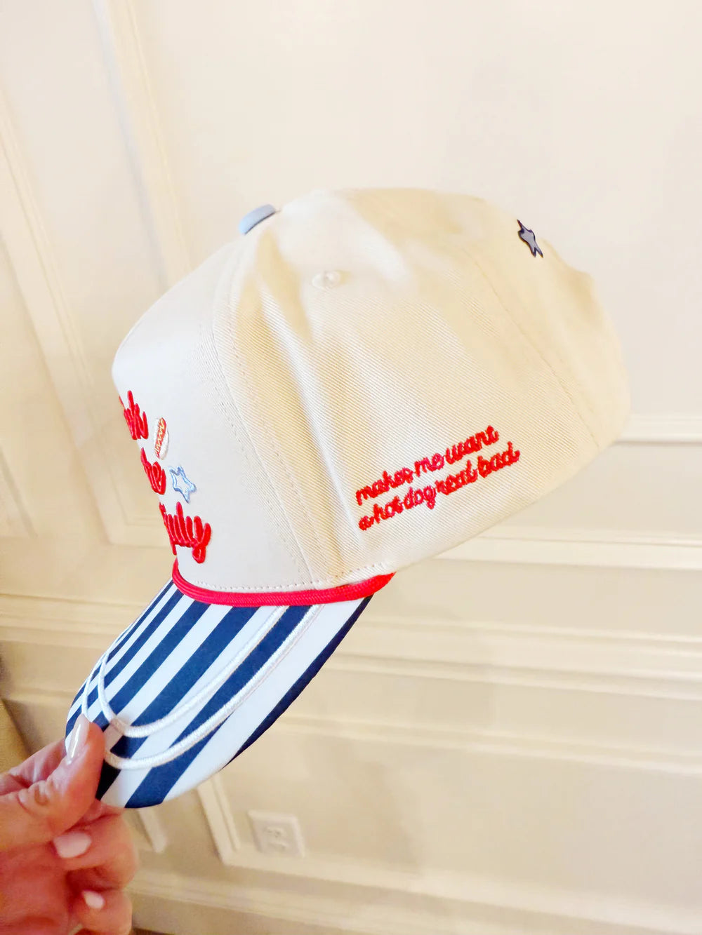 Cap with text and stripes held by a hand against a neutral background