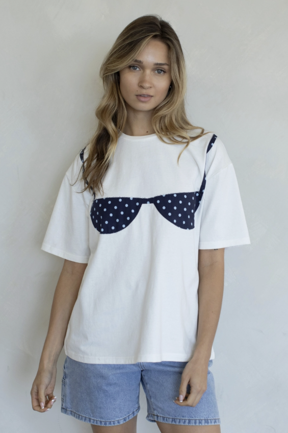 Woman wearing white tee with blue bathing suit on plain background