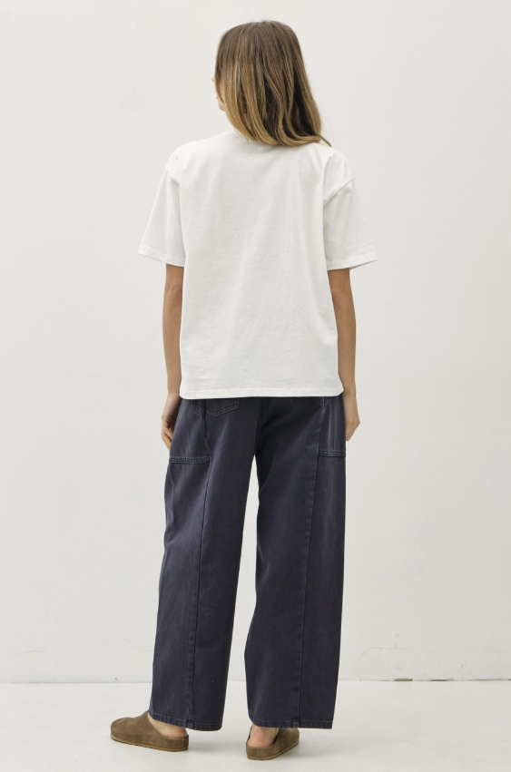 A model shown from the back wearing a white short-sleeve t-shirt and dark navy wide-leg pants, standing against a plain white studio background.