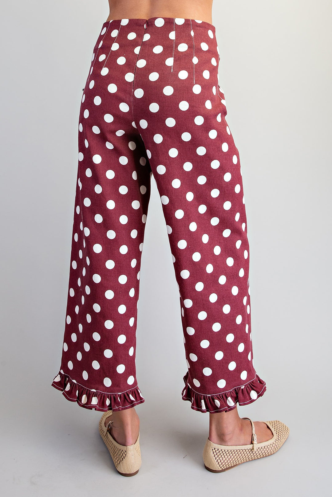 Maroon pants with white polka dots and ruffles on a gray background