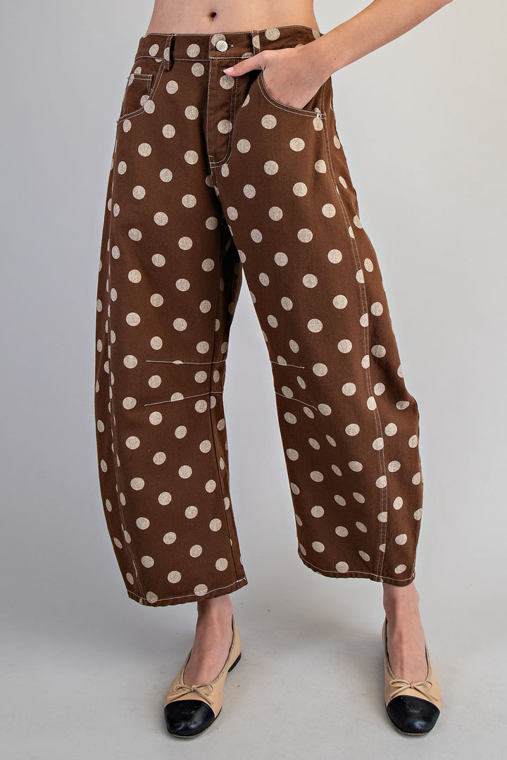 Woman wearing brown polka dot pants on plain background