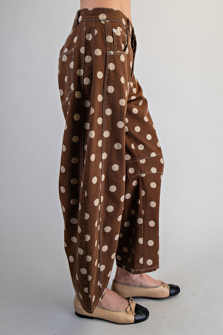 Woman wearing brown polka dot pants on plain background