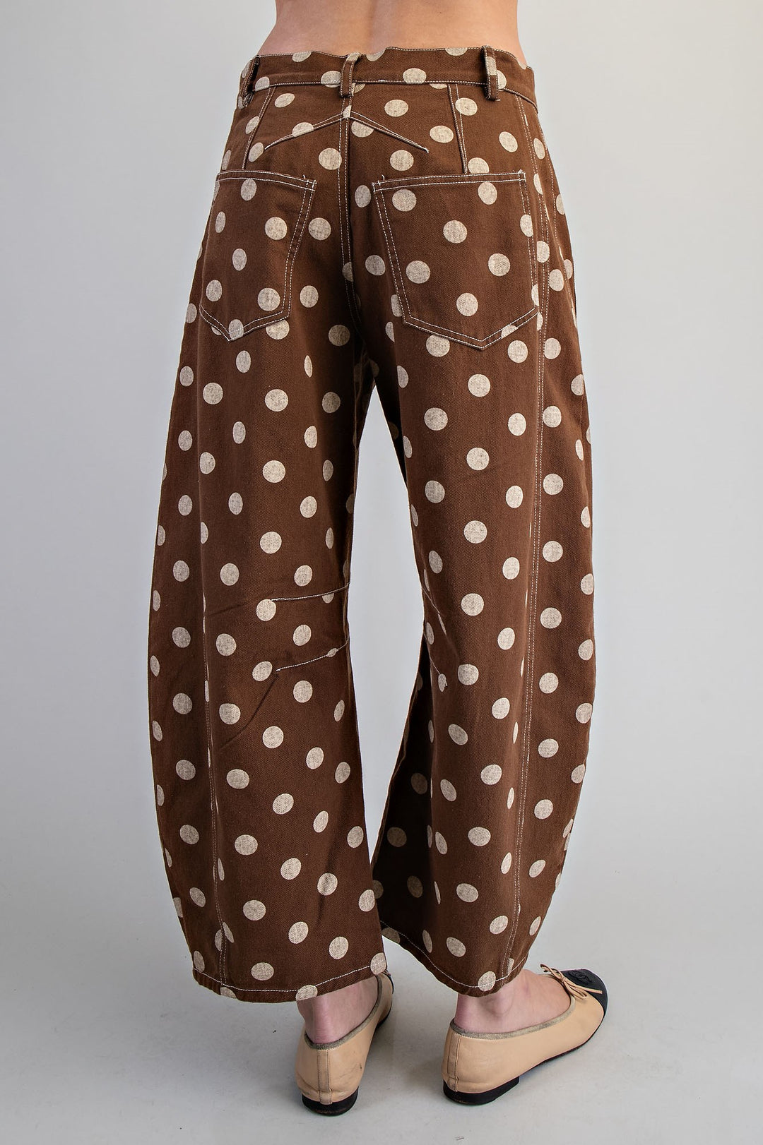 Woman wearing brown polka dot pants on plain background