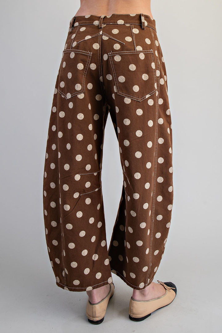 Woman wearing brown polka dot pants on plain background